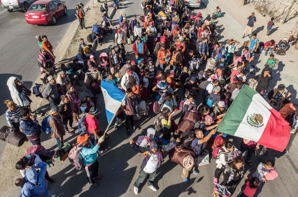 Migrantes cantan y ondean banderas al llegar a Tijuana San Diego